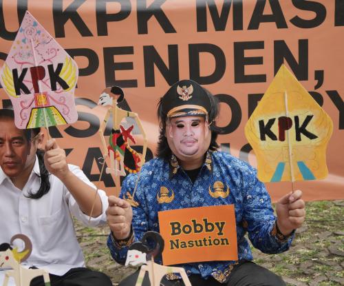 Ilustrasi: Pemeran bertopeng Bobby Nasution dan Jokowi sedang memainkan wayang berlogo KPK