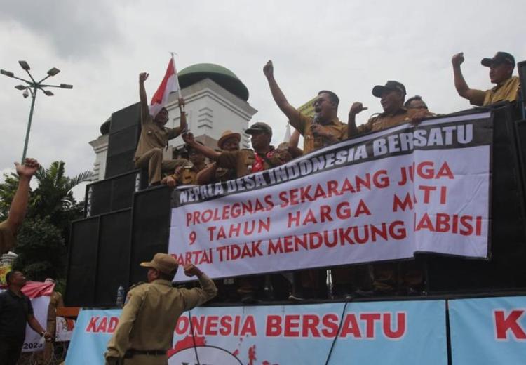 Kades demo di depan gedung DPR sambil memegang spanduk bertuliskan tuntutan jabatan 9 tahun